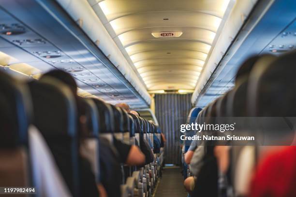 passengers are sitting and sleeping on an airplane. - aisle seat airline stock-fotos und bilder