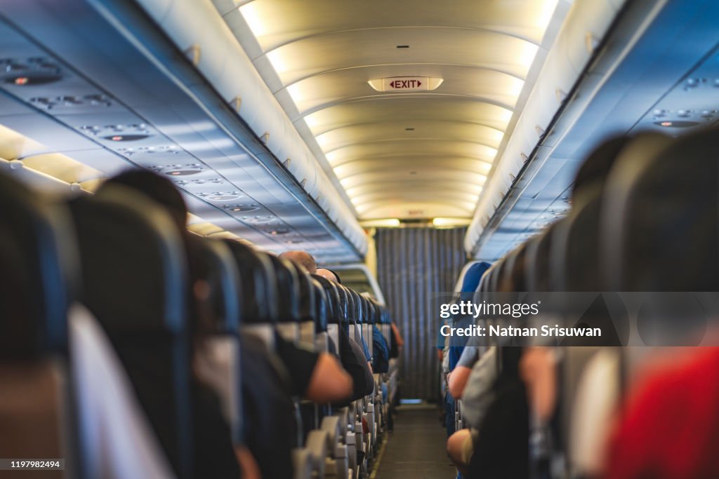 Passengers are sitting and sleeping on an airplane.
