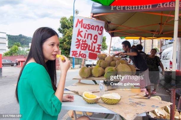 mulher asiática que come o durian em um lado da estrada da tenda do mercado de bentong - durian - fotografias e filmes do acervo