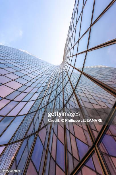 blue sky reflecting on a curved glass skyscraper - hochbau stock-fotos und bilder