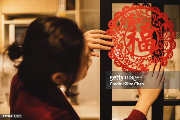 chinese new year celebration-woman decorating the house with paper cutting craft - chinese window pattern stockfoto's en -beelden