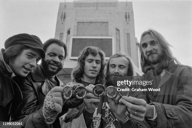 British rock band Genesis holding pins which read "Rainbow, Rock Again" outside the Rainbow Theatre in London, UK, January 1977; they are Steve...