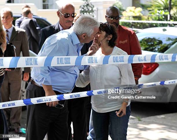 Amy Winehouse's mother Janis Winehouse shares a kiss with Amy's father Mitch Winehouse as they look at floral tributes left at her house by fans on...