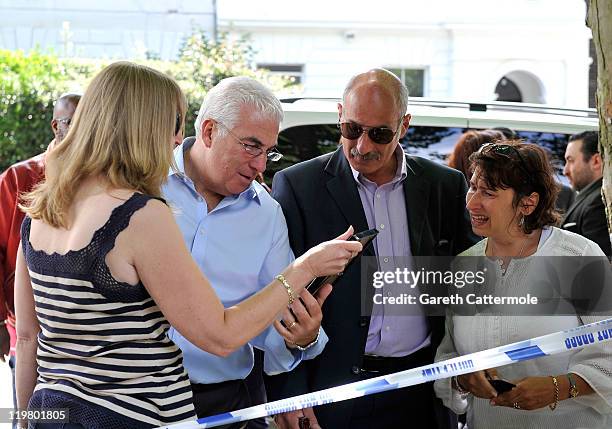 Amy Winehouse's mother Janis Winehouse and Amy's father Mitch Winehouse and his second wife Jane look at floral tributes left at her house by fans on...