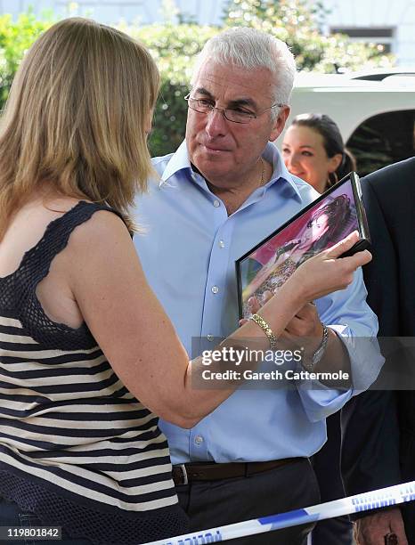 Amy Winehouse's father Mitch Winehouse stands with his second wife Jane as he looks at tributes left at her house by fans on July 25, 2011 in London,...