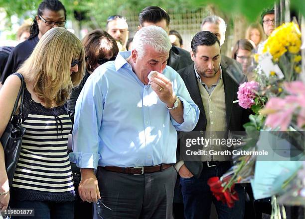 Amy Winehouse's father Mitch Winehouse and brother Alex Winehouse look at floral tributes left at her house by fans on July 25, 2011 in London,...