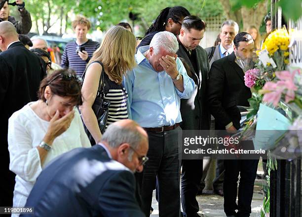 Amy Winehouse's father Mitch Winehouse brother Alex Winehouse her former boyfriend Reg Traviss and her mother Janis Winehouse look at floral tributes...