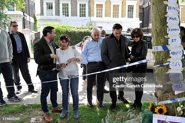 Amy's father Mitch Winehouse and mother Janis Winehouse look at floral tributes with their son Alex Winehouse and Amy's former boyfriend Reg Traviss...