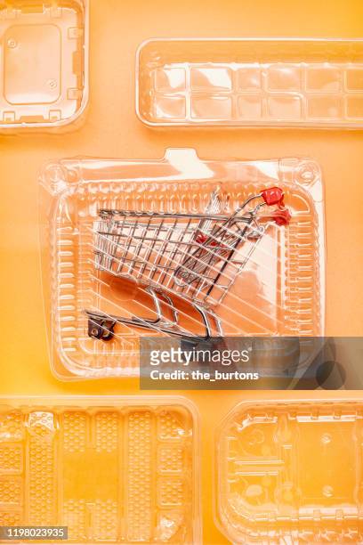 shopping cart in plastic packaging on orange colored background - box packaging mockup stock pictures, royalty-free photos & images