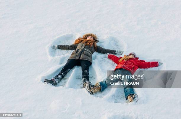 full length of girls making snow angels - family sunset stock pictures, royalty-free photos & images