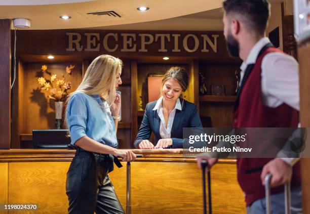 business woman checking in at the hotel reception desk - doorman stock pictures, royalty-free photos & images