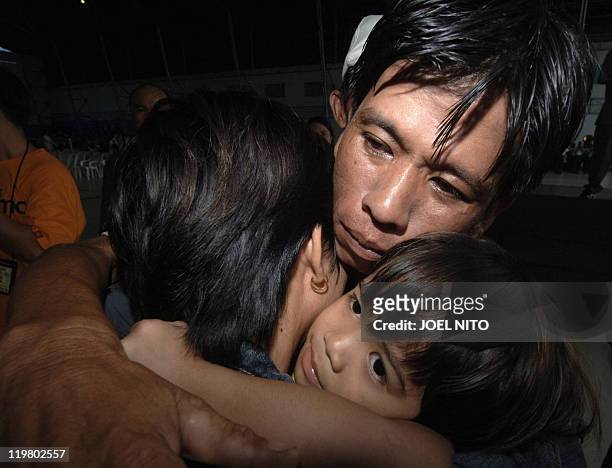 Man embraces his wife , one of the 230 Filipinos evacuated from conflict-stricken Lebanon shortly after arriving at Villamor air base in Manila, 23...