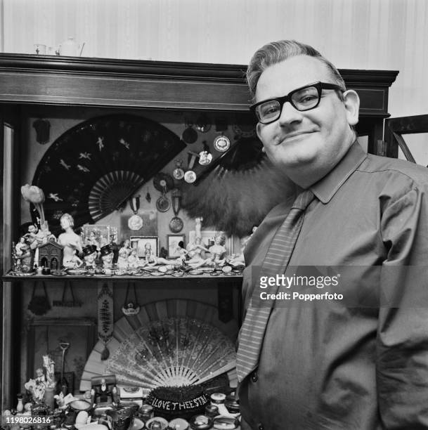 English actor, comedian and writer Ronnie Barker posed with a cabinet of curios at home in May 1968.