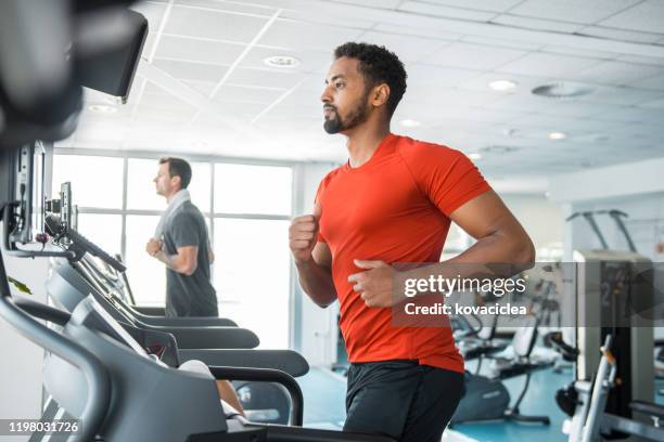 dos amigos varones corriendo en la cinta de correr en el gimnasio - treadmill fotografías e imágenes de stock