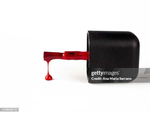 red nail polish brush and a drop of enamel falling against a white background - esmalte de uñas rojo fotografías e imágenes de stock