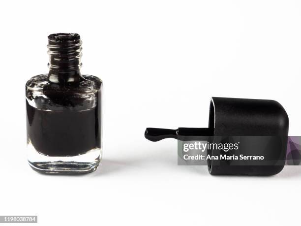 an open canister and black nail polish brush against white background - esmalte de uñas negro fotografías e imágenes de stock