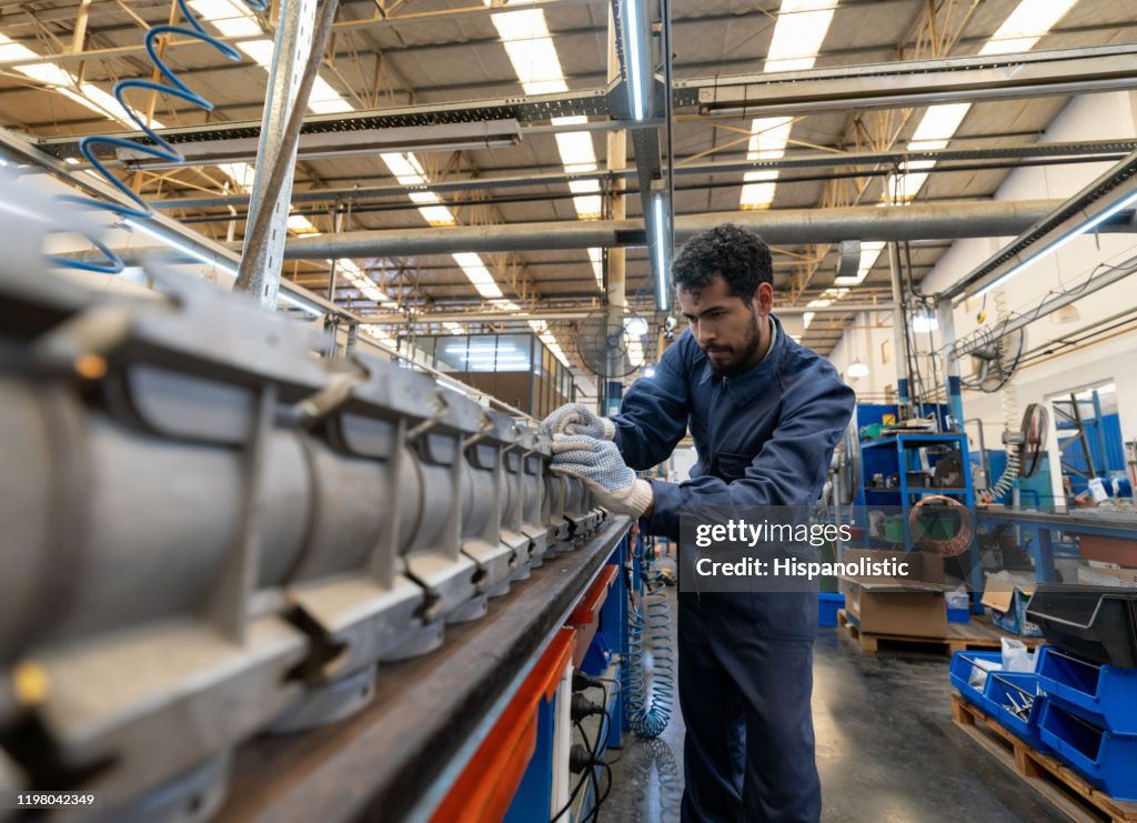 Joven con enfoque latinoamericano que trabaja en una fábrica de bombas de agua de fabricación