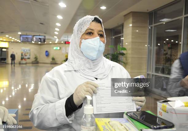 An Egyptian Quarantine Authority employee holds out a health form to be filled in by incoming travellers at Cairo International Airport on February 1...