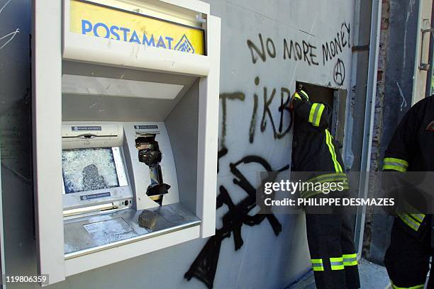 Italian firemen check an automatic teller machine broken during clashes between police and anti-globalisation activists in Genoa 21 July 2001. Police...