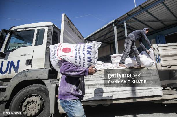 Man transports a sack of flour as people come to receive food aid from a United Nations Relief and Works Agency distribution centre in the Khan Yunis...