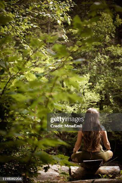 jonge vrouw ontspannen en mediteren in de natuur - lotuspositie stockfoto's en -beelden
