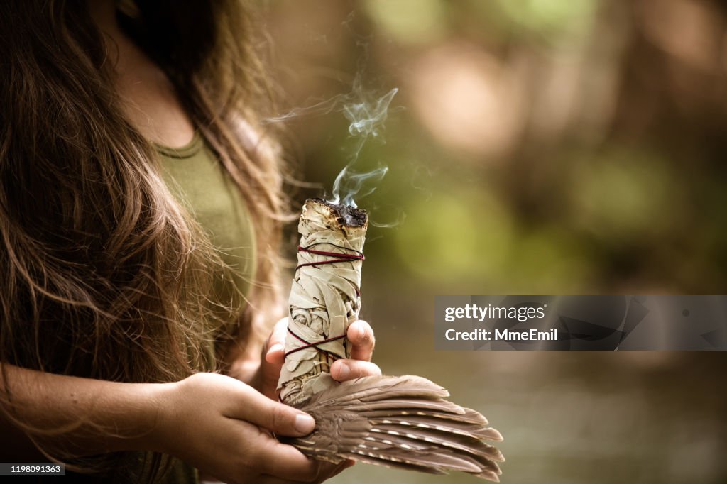 Alternativ medecine, ung kvinna utför en renings ritual med salvia