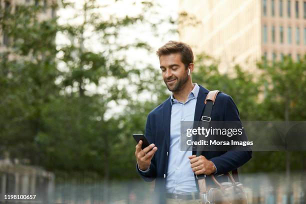 smiling confident businessman using smart phone - business people outside stock-fotos und bilder