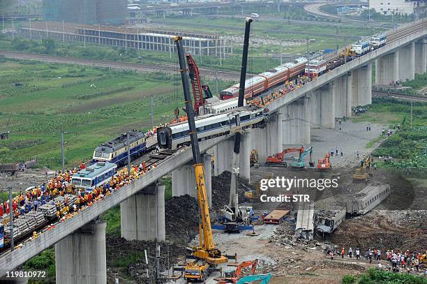 This photo taken on July 24, 2011 shows workers clearing wreckage of mangled carriages after a Chinese high-speed train derailed when it was hit from...