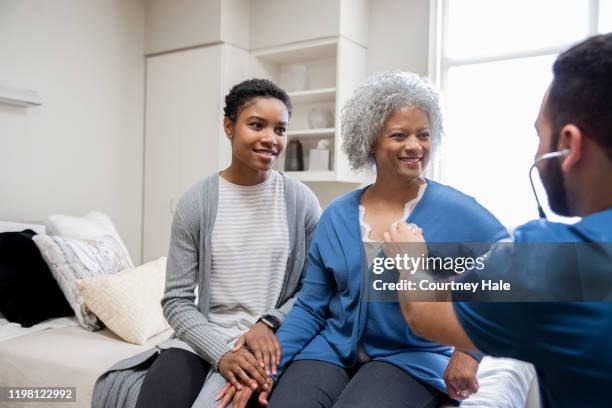 daughter sitting with mother at her check up appointment - medicaid stock pictures, royalty-free photos & images