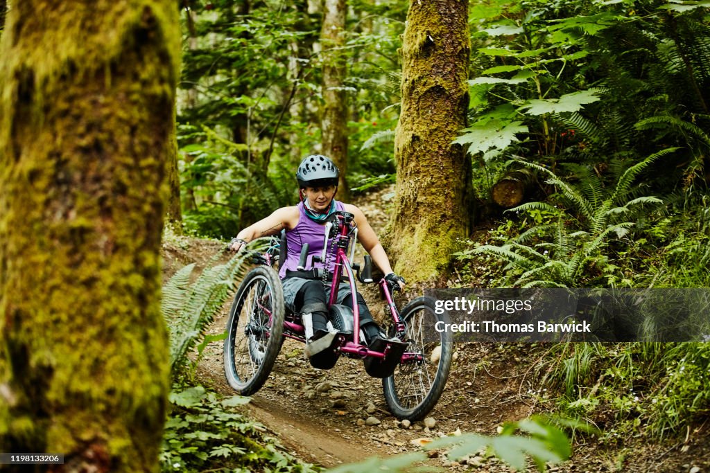 Female wheelchair athlete descending trail on adaptive mountain bike