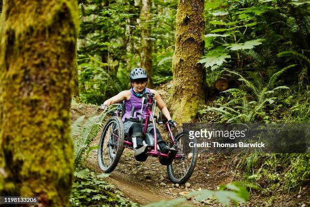 female wheelchair athlete descending trail on adaptive mountain bike - forward athlete stock pictures, royalty-free photos & images