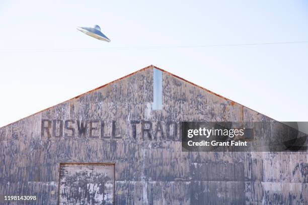 a flying saucer flying above warehouse. - ufo saucer stock pictures, royalty-free photos & images