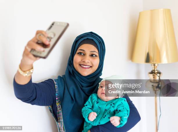 muslim mother and baby taking selfie with smartphone - arab mother and daughter taking selfie imagens e fotografias de stock