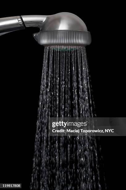 shower head with water against black background - shower head stock pictures, royalty-free photos & images