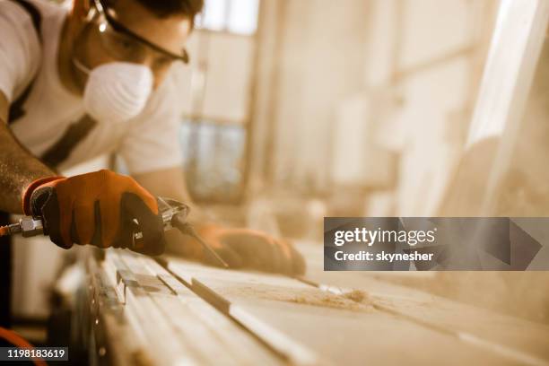 close up of carpenter using air pump to blow sawdust from a plank. - sawdust stock pictures, royalty-free photos & images