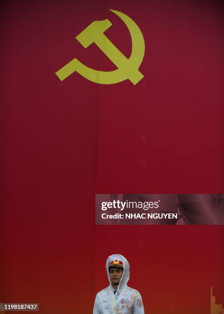 Policeman stands in front of a poster to mark the 90th anniversary of the communist party of Vietnam in Hanoi on February 3, 2020. - Vietnam...