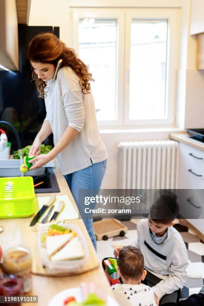 mutter in der küche waschen geschirr und mit smartphone - busy mum mess stock-fotos und bilder