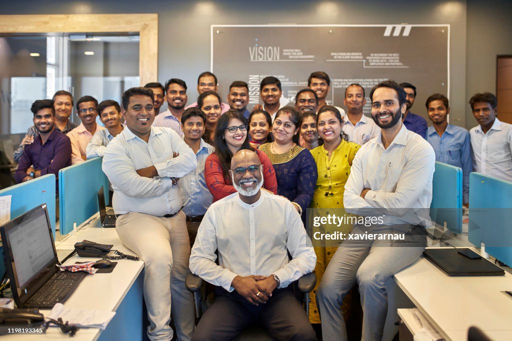 Proud Indian CEO Posing with Smiling Company Staff in Office