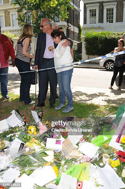 Amy Winehouse's mother Janis Winehouse is comforted as she looks at the floral tributes left outside her Camden Square home on July 25, 2011 in...