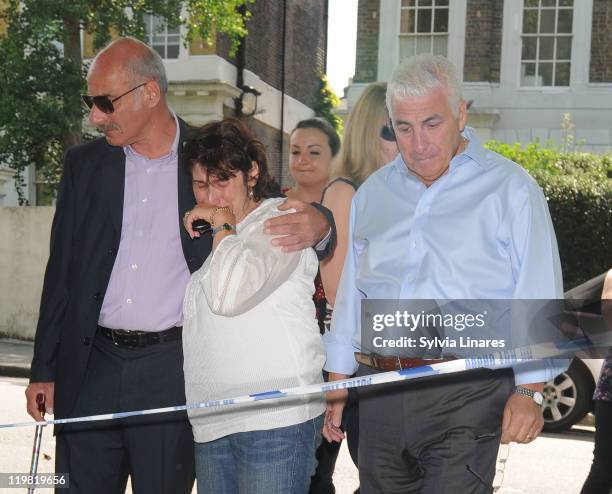 Amy Winehouse's mother Janis Winehouse and father Mitch Winehouse look at the floral tributes left outside her Camden Square home on July 25, 2011 in...