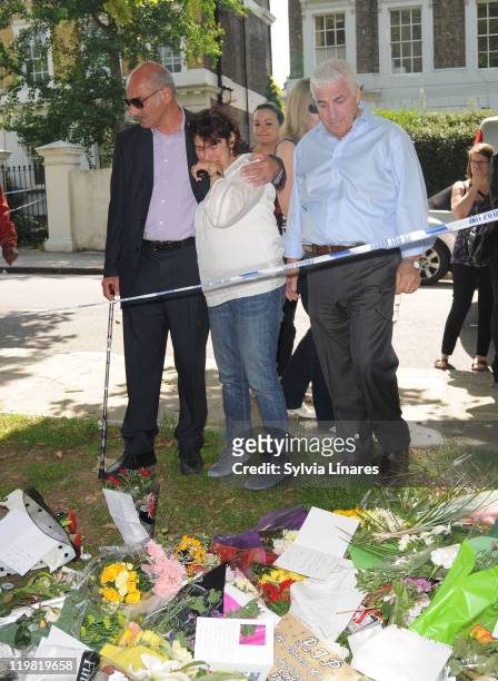 Amy Winehouse's mother Janis Winehouse and father Mitch Winehouse look at the floral tributes left outside her Camden Square home on July 25, 2011 in...