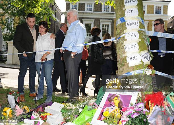 Amy Winehouse's brother Alex Winehouse, mother Janis Winehouse and father Mitch Winehouse look at the floral tributes left outside her Camden Square...