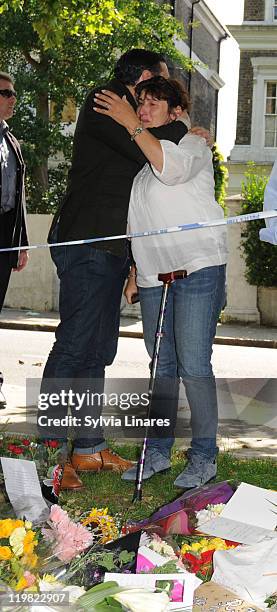 Amy Winehouse's brother Alex Winehouse comforts his mother Janis Winehouse as they look at floral tributes seen at her Camden Square home on July 25,...