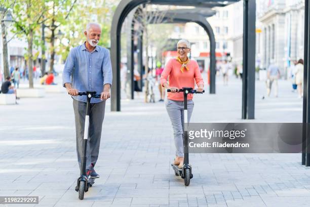 modern senior couple with electric scooter - couple scooter stock pictures, royalty-free photos & images