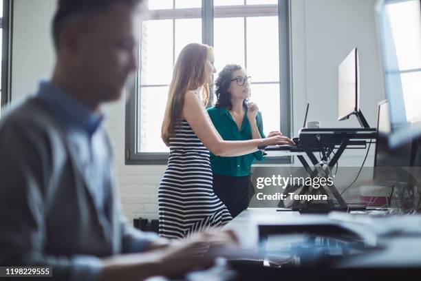 zwei geschäftsfrauen, die am stehtisch arbeiten. - ergonomie stock-fotos und bilder