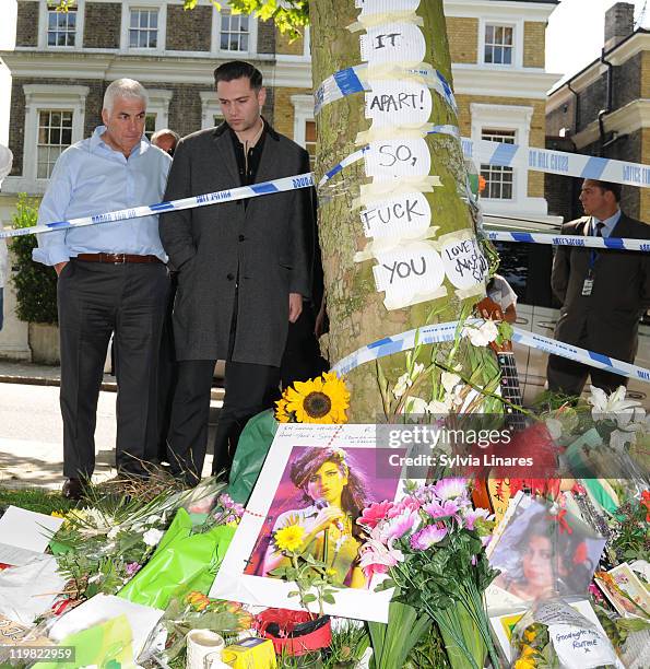 Amy Winehouse's father Mitch Winehouse and ex boyfriend Reg Traviss are seen looking at the floral tributes outside her Camden Square home on July...