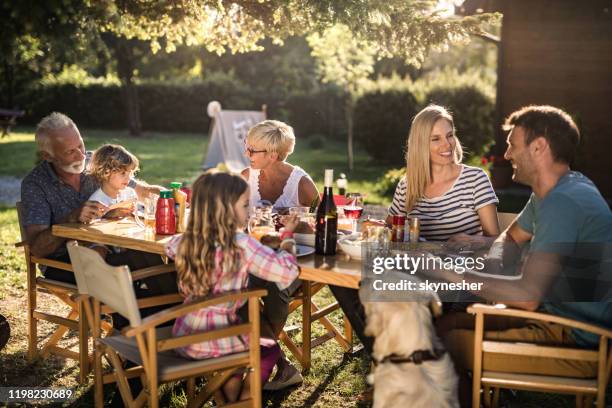 happy extended family enjoying in conversation during lunch time in the backyard. - family backyard imagens e fotografias de stock