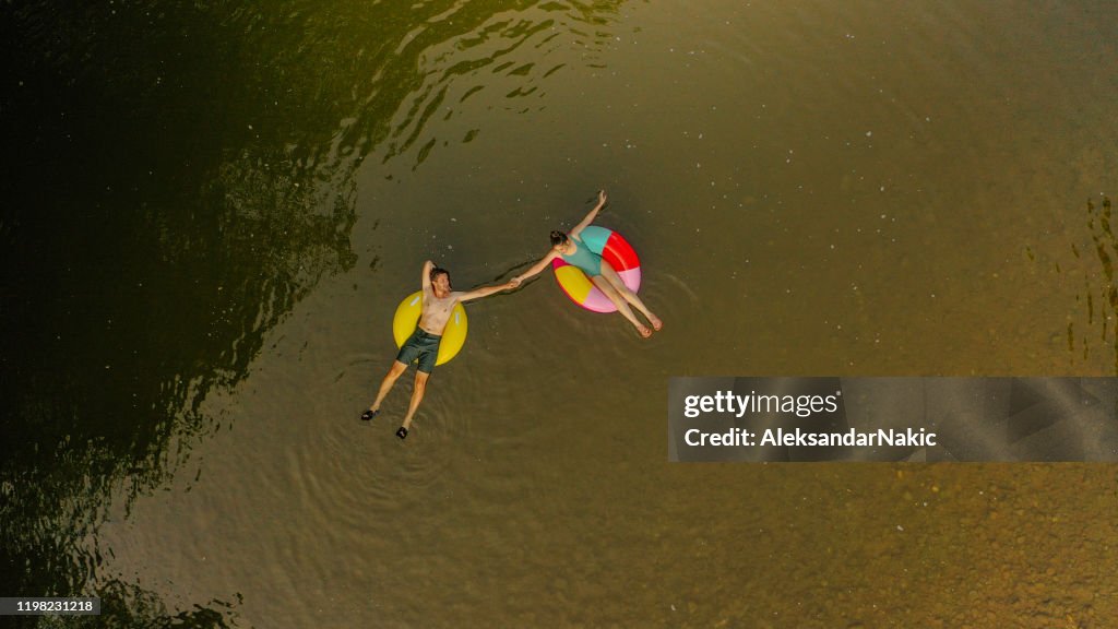 Young couple on inflatable rings in the river