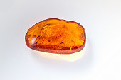 Amber stone. Mineral amber. Rosin yellow amber. Sunstone on a beach of pebbles background.