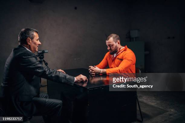 mannelijke gevangene zittend in ondervrachting kamer met detective - point interrogation stockfoto's en -beelden
